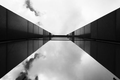 Directly below shot of glass building against cloudy sky