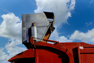 Low angle view of crane against building against sky