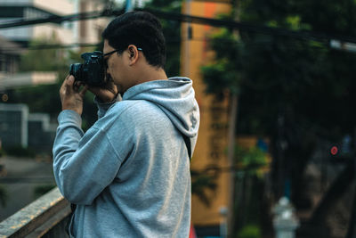 Side view of photographer in hooded shirt photographing