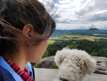 Rear view of woman with dog against sky