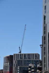 Construction site by buildings against clear blue sky