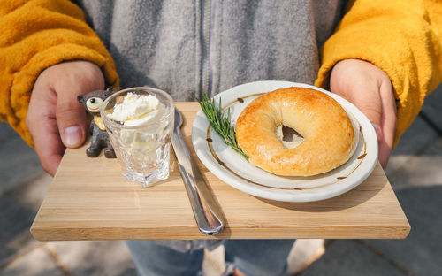 Close-up of hand holding bagel on the plate