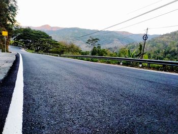 Surface level of road by mountains against sky