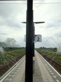 Railroad tracks against cloudy sky