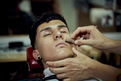 A young boy is being shaved by a barber