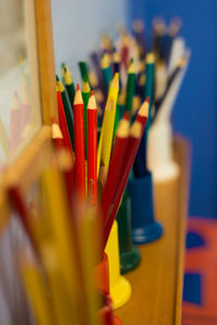 Colorful pencils in desk organizers on shelf