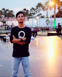 Portrait of young man standing in city during sunset