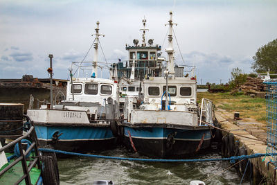 Boats moored at harbor against sky