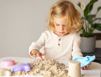 Caucasian,blonde,curly-haired toddler,baby playing with sand.kid development,motor sensoric skill