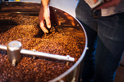 Cropped image of man grinding coffee beans on espresso maker at cafe