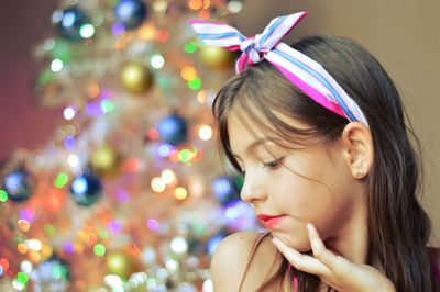 Close-up of girl against christmas tree at home
