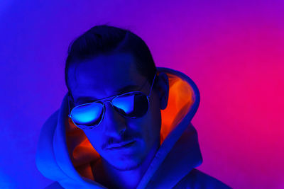 Close-up of young woman wearing sunglasses against blue background