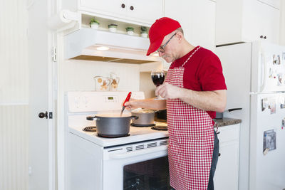 Senior man preparing food while standing in kitchen