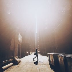 Man passing on road against buildings during sunny day