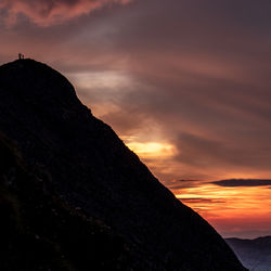 Scenic view of silhouette mountains against orange sky