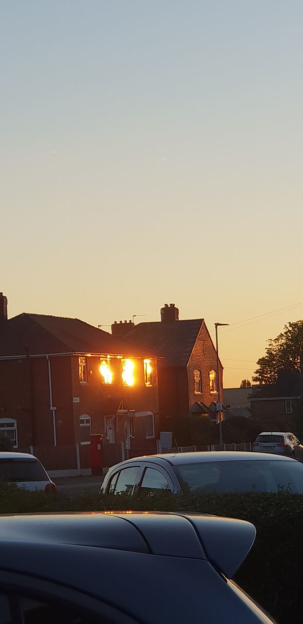 STREET AMIDST BUILDINGS AGAINST SKY DURING SUNSET