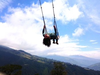 Low angle view of carefree woman swinging against sky