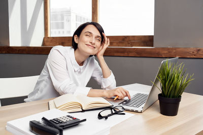 Woman using laptop while sitting by table