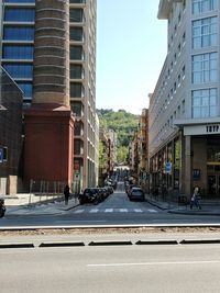 Road amidst buildings in city against sky