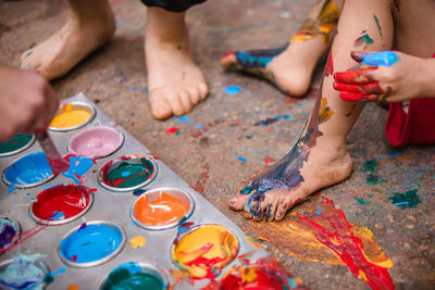 Children feet and tray of multicolored paint on the floor 