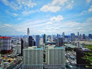 Aerial view of buildings in city against cloudy sky