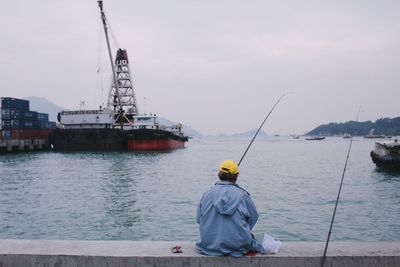 Rear view of man working in sea against sky