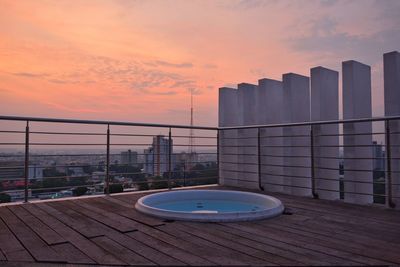 Modern buildings by swimming pool against sky during sunset