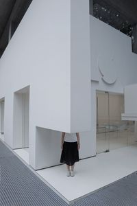 Rear view of woman walking on umbrella against building