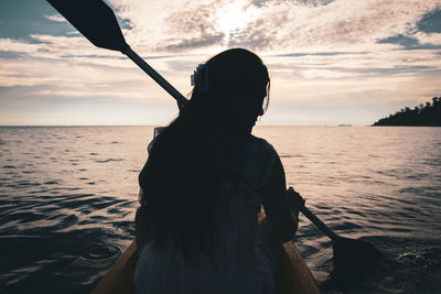 Silhouette person holding sea against sky at sunset