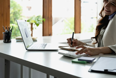 Midsection of businesswoman using laptop on table