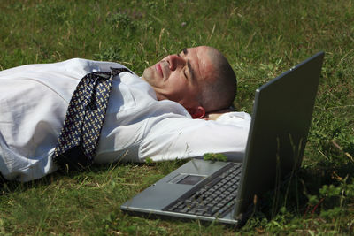 Rear view of man using laptop on field