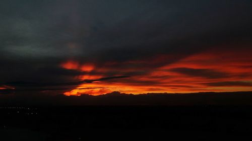 Silhouette landscape against dramatic sky during sunset