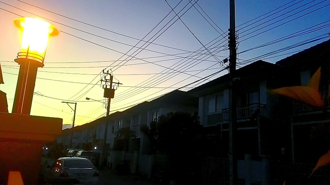 power line, electricity, street light, lighting equipment, electricity pylon, illuminated, cable, power supply, built structure, building exterior, architecture, transportation, sunset, sky, power cable, low angle view, street, clear sky, dusk, electric light