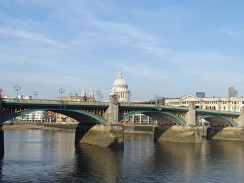 Arch bridge over river against sky in city