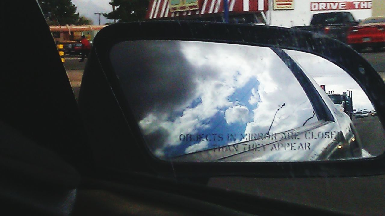 transportation, mode of transport, land vehicle, car, text, sky, vehicle interior, western script, communication, close-up, part of, reflection, cropped, cloud - sky, car interior, road, street, travel, no people, side-view mirror