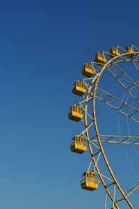 Low angle view of ferris wheel against clear blue sky