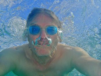 Portrait of shirtless man swimming in pool