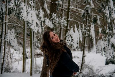 Young woman standing against trees