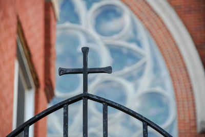 Low angle view of cross on railing against building