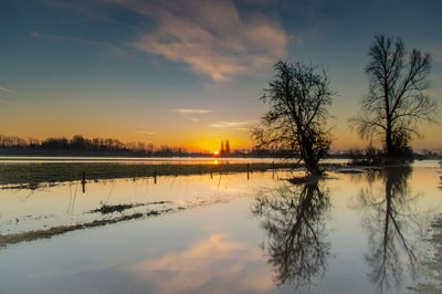 Scenic view of lake with silhouette trees reflection at sunset