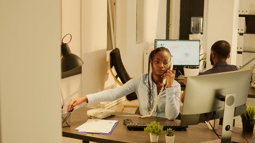 Young woman using mobile phone while working at office