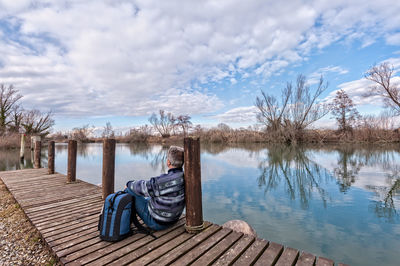 Wooden posts on jetty by lake against sky