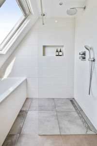 Shower in front of a bathtub in the bright attic bathroom