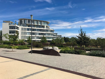 Footpath by building against sky on sunny day