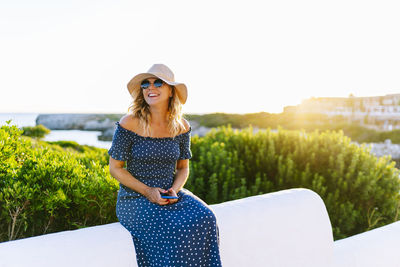 Young woman wearing hat standing against sky