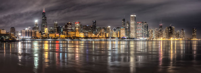 Panoramic view of illuminated city against cloudy sky at night