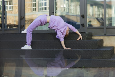 Woman exercising bridge position on staircase in front of glass door