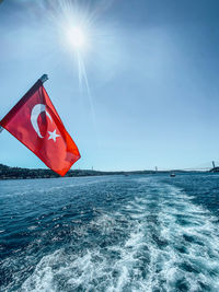 Red flag on sea against sky