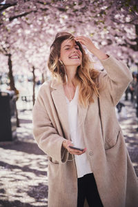 Young woman standing under cherry blossom