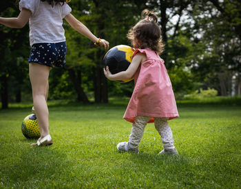 Two girls with a soccer ball on the lawn.